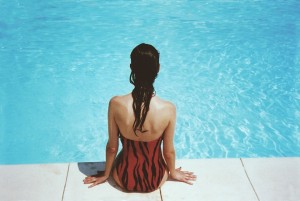 woman sitting by swimming pool