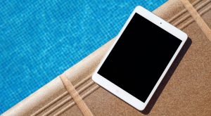 iPad sitting on the edge of a dock next to an inground swimming pool