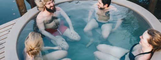 four people sit in a hot tub outdoors