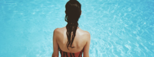 Woman with dark hair sits at the edge of a hot tub looking down