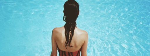 Woman with dark hair sits at the edge of a hot tub looking down