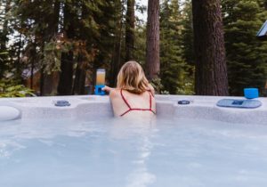 blonde woman wearing red bikini sits in hot tub with a beverage
