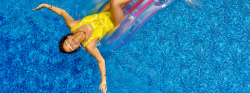 woman in yellow bathing suit floats on a pool floaty in a vinyl-lined pool